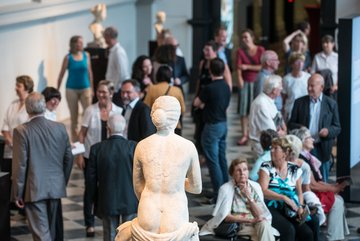 Besucher in der Ausstellung, mittig eine nackte Frauenskulptur in Rückenansicht