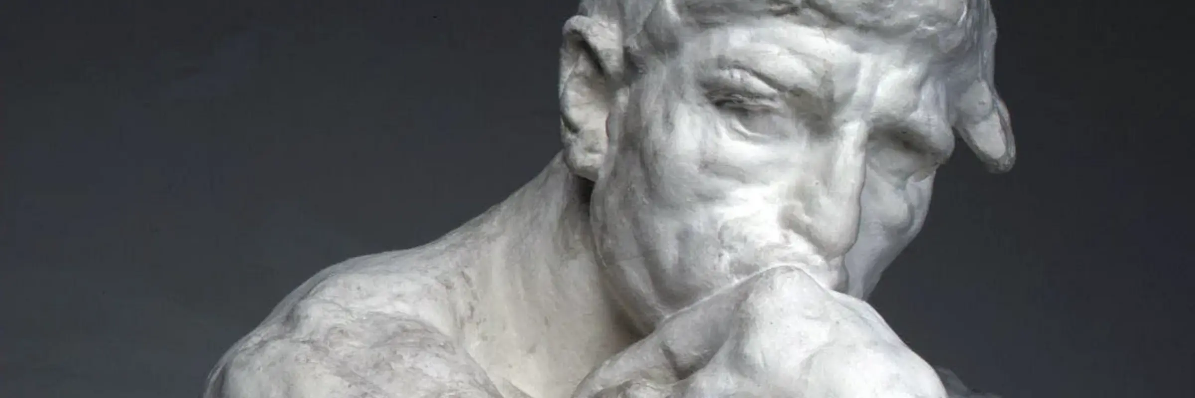 Eine Statue eines Mannes, der im Nachdenken seinen Kin auf den Faust stützt 