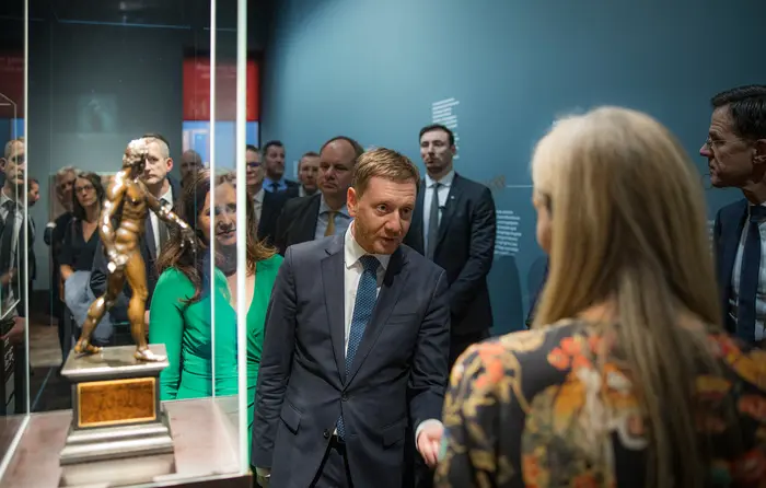 Eine Pressekonferenz in einem Ausstellungsraum mit Bronzefiguren 