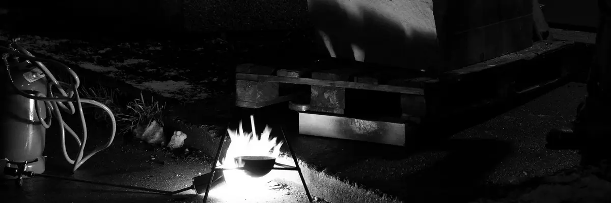 Foto mit einem Bunzenbrenner und einem Stein auf einer Holzpalette