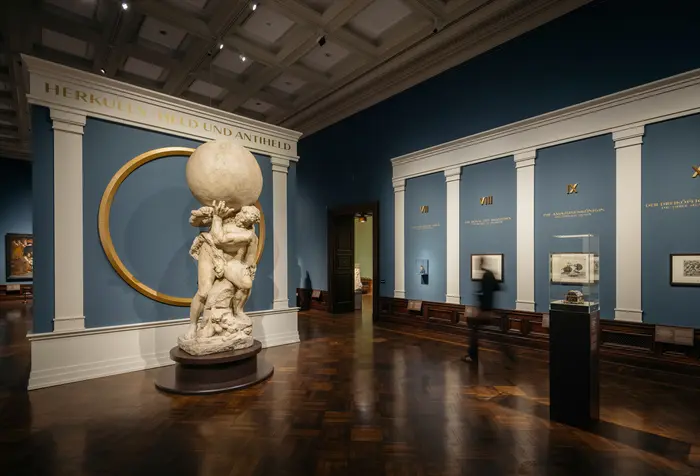 Raumansicht mit einer großen Figur, die eine Kugel trägt